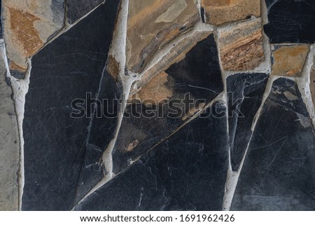 The dirty texture of the brown and dark gray stone slate background. The wall is plastered with cement and black slate.