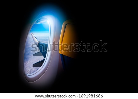 Black background with copy space look of window seat frame of airplane flight see view of clouds sky, wing travel during coronavirus risk crisis fall demand of flight cancel 