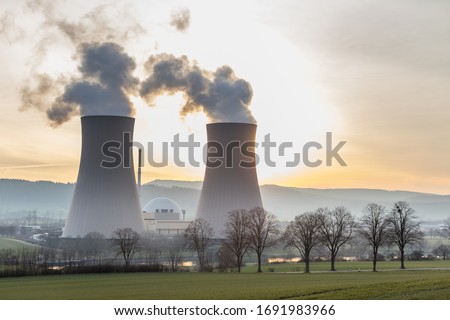 Cooling towers of a nuclear power plant in the back light Royalty-Free Stock Photo #1691983966