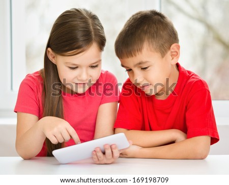 Children are using tablet while sitting at table, isolated over white