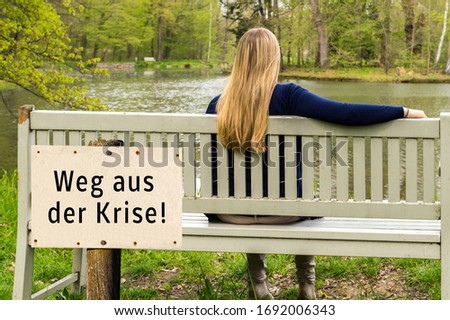 Young woman sitting on the bench with way out of the crisis! sign in german