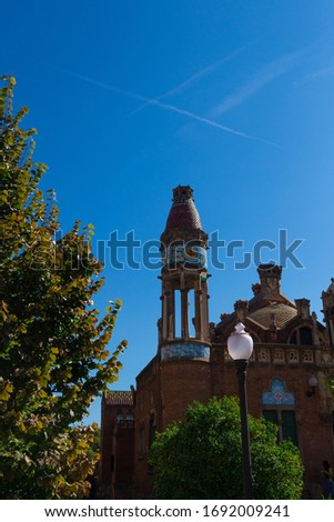 Buildings and walls of red brick, high spiers of the tower and arched windows, elements of architectural decoration of buildings. On the streets in Catalonia, public places.