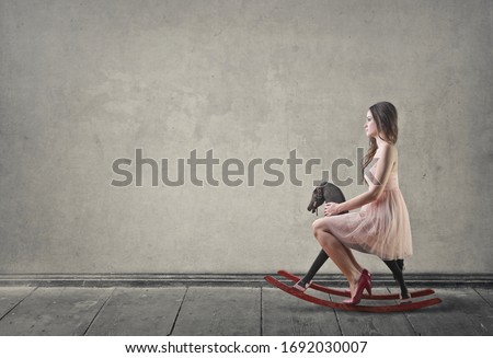 Pretty girl sitting on a rocking horse.