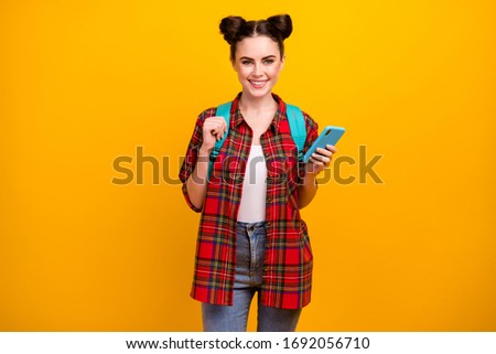 Photo of beautiful student lady hold telephone freelancer work study go lesson lecture september wear blue bag casual checkered shirt jeans isolated yellow color background