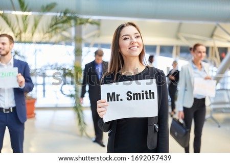 Businesswoman with name tag at airport picking up from a guest