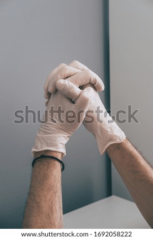 A medical worker in rubber latex gloves on his hands prays for recovery of patients . Concept of protection against coronavirus   