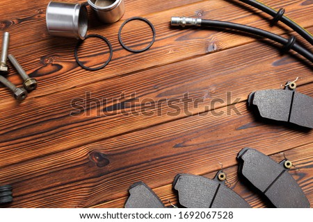 brake parts on wooden background  brake pads, disc, brake hose, guides, cylinders
