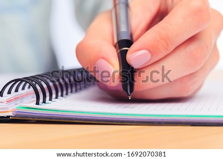female hands write in a notebook . Office place . Close up view 