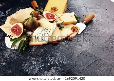 Cheese plate served with figs, various cheese on a platter on rustic table
