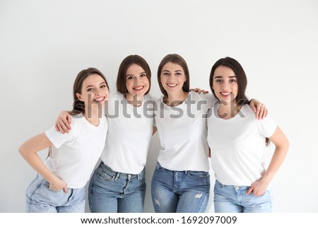 Beautiful young ladies in jeans and white t-shirts on light background. Woman's Day