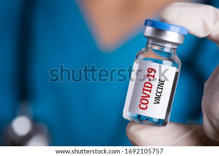 Female doctor with a stethoscope on shoulder holding syringe and COVID-19 vaccine. Healthcare And Medical concept. Royalty-Free Stock Photo #1692105757