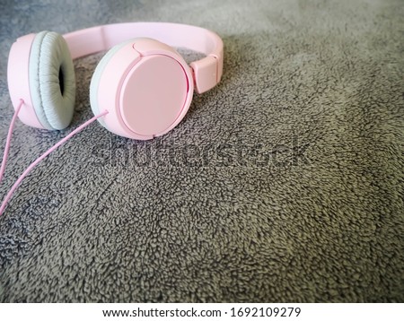 Large pink headphones on a gray fur surface