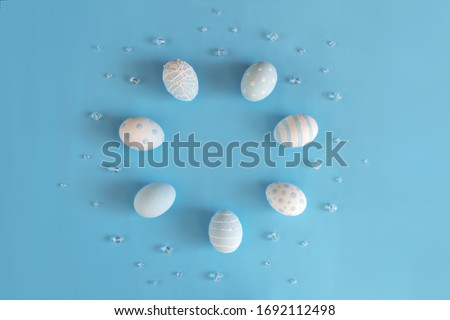 Festive Easter circle frame. Beautiful panted eggs polka dots and stripes with beads on pastel blue background with copy space. Nature celebration design. Flat lay, Top view.