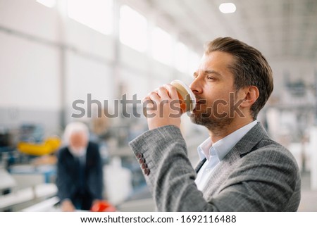 Young businessman drinking coffee at work. Handsome businessman in factory
