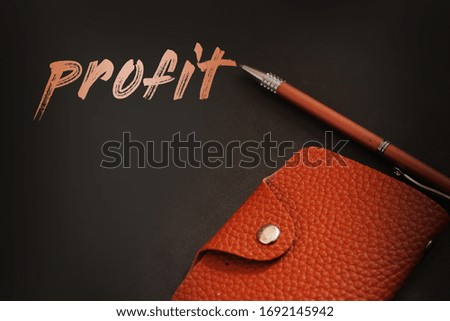 Profit word, a pen and wallet on dark background. Business startup profit concept.