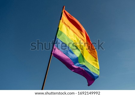 Gay rainbow flag on a sunny summer day with blue sky