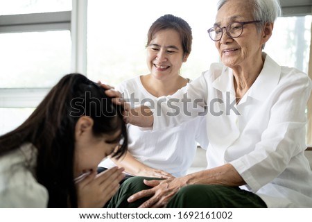 Happy smiling asian senior woman is stroking her child girl head, welcoming her family,loving daughter with her mother comes to visit her grandmother at home,pay respect to the elderly,Thai culture Royalty-Free Stock Photo #1692161002