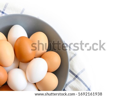 chicken eggs white and brown color in a gray plate on a checked kitchen towel on a white table. concept farm products and natural nutrition. space for text