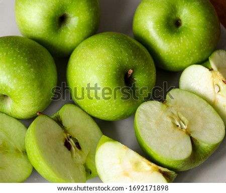 whole and sliced green apples on a plate