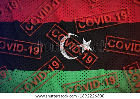 Libya flag and many red Covid-19 stamps. Coronavirus or 2019-nCov virus concept