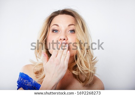 Isolated portrait of a beautiful young woman with blond hair. Smiling girl gives a kiss