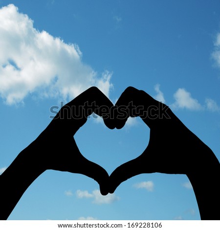 Concept conceptual human male or man and woman hands in love, Valentines shape or symbol of heart over blue sky background, metaphor to romance, romantic, wedding, honeymoon, holiday, vacation couple