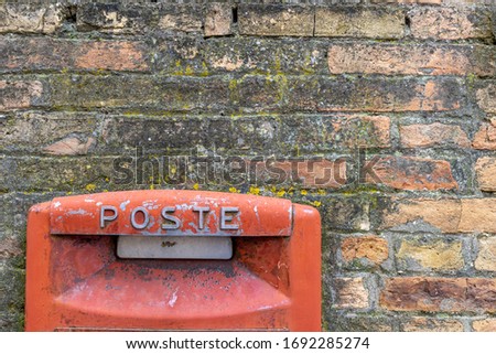 red old italian mailbox on a brick wall