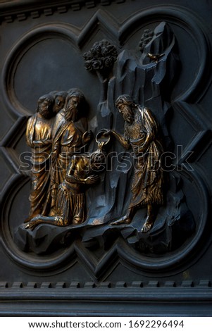 Metallic carving of men group. Bible scene with saint and followers. Religious ritual image. Fragment of vintage door of Florence baptistery.