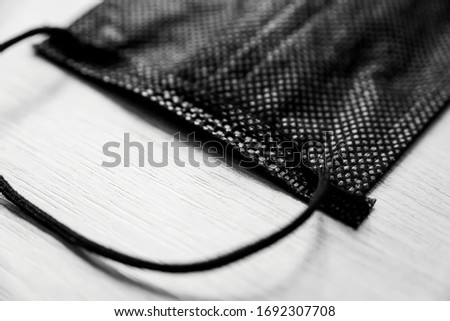 black medical mask made of non-woven synthetic materials (spunbond). A modern mask consists of a filter layer, between two outer layers (three-layer masks), as well as a flexible aluminum insert.