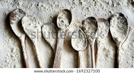 Many wooden spoons sprinkled with wheat flour. Baking concept on flour background. Photo filter effect, HDR. Top view.