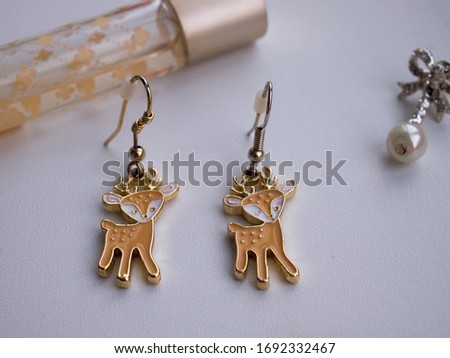 Earrings and perfume on a light background