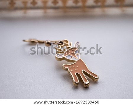 Earring in the form of a deer with a perfume-roller on a white background in isolation