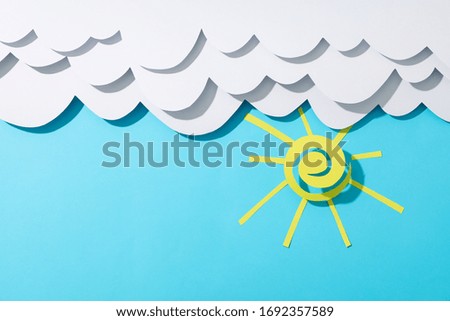 Paper clouds and sun on blue background. Travel