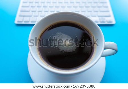 Creative flat lay photo of workspace desk. Top view office desk with keyboard and coffee cup on blue color background.