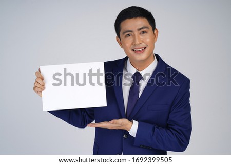 Happy Asian smiling young business man holding blank white small board, isolated on white background, asian model