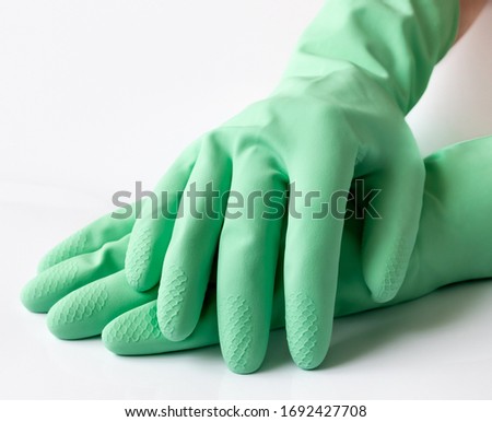 Hand in green latex dishwashing gloves on a white background