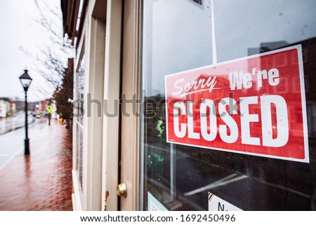 A “sorry we’re closed” sign hangs in a downtown storefront.