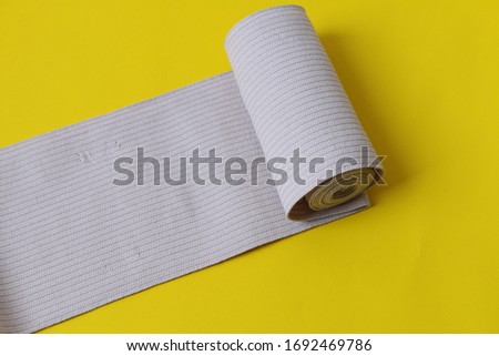 Sterile bandage on yellow background. Medical bandage roll. Roll of bandage. Sterile bandage roll on yellow.