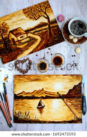 Pictures drawn by coffee, brushes, coffee beans and a cup on a light wooden background. Top view
