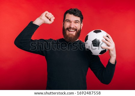 happy young man celebrating victory and holding soccer ball