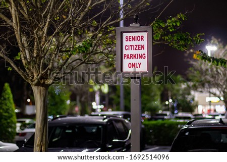 A senior citizen parking only sign for the retired population at night in a strip mall parking.