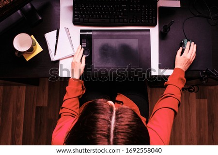 a cenital workspace with female hands working with graphic tablet