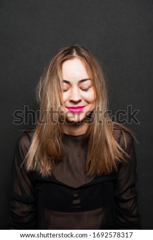 Girl in a black dress on a black background laughs and rejoices, feel happiness