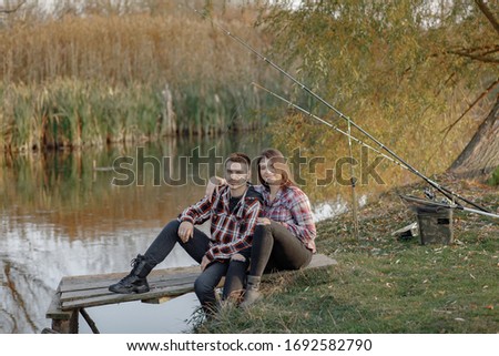 Couple by the river. Guy in a red shirt. Man in a fishing.