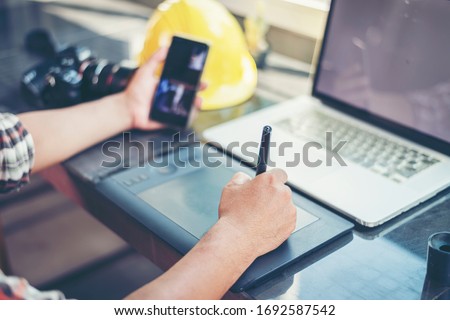 Work from home.Professional graphic editor retouching images with stylus pen in hand.Retoucher processing photos on laptop computer using tablet.Creative freelancer retouched image on notebook