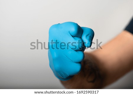 Man's hand in blue medical gloves is showing his fist Royalty-Free Stock Photo #1692590317