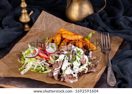 Meat on trochanter with cheese sauce, served with potatoes and fresh vegetables, tomatoes, cucumbers., radish and onions
