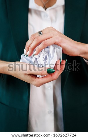 Tired on work woth documents: Female hands with green nails hold a crumpled round piece of paper