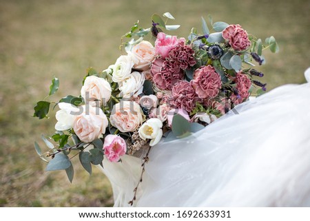 wedding bouquet with roses, carnations, tulips, succulents, lavender and herbs on a background of grass and a white wedding dress. Bouquet of fresh flowers. Wedding floristry. Natural flowers.
