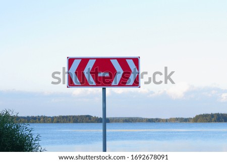 Road sign for the exit in different ways by the lake